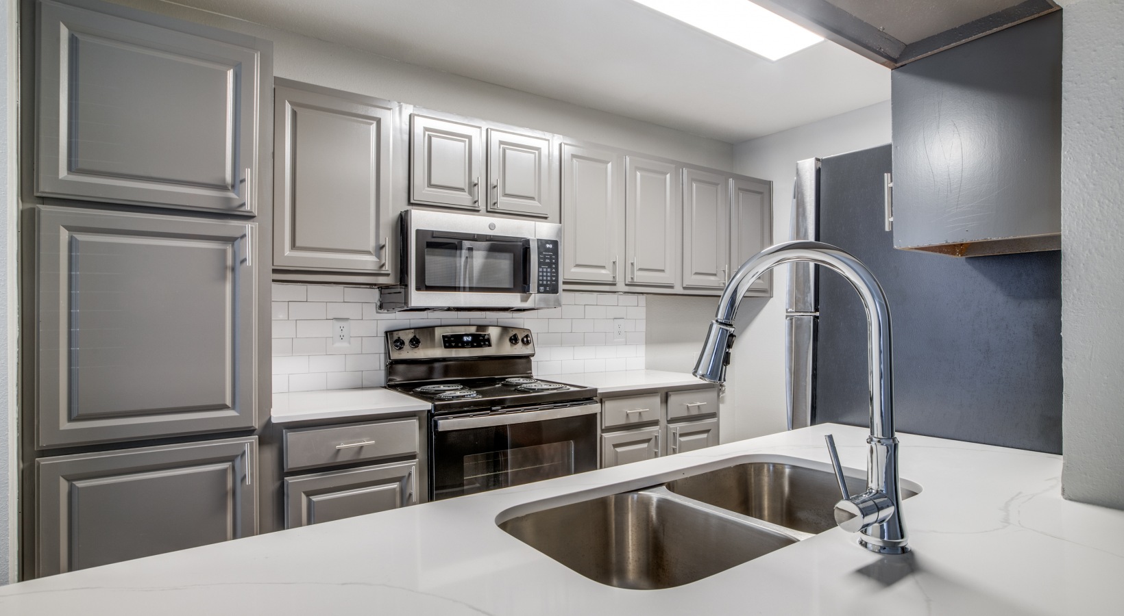 a kitchen with stainless steel appliances and gray cabinets at The  Argyle