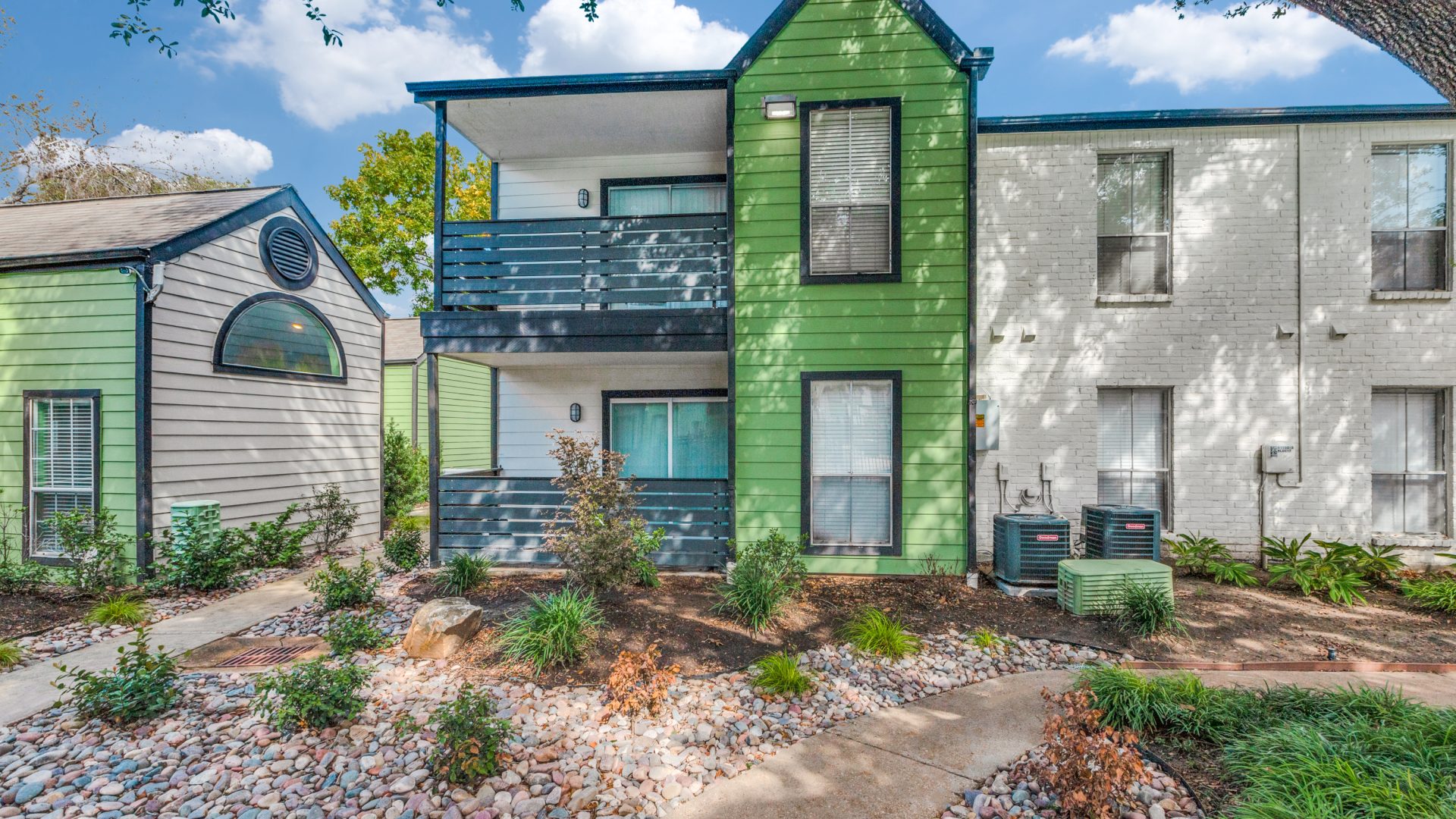 the exterior of an apartment building with green siding and a green fence at The  Argyle